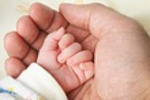 Mão de pai a segurar mão de bebê
